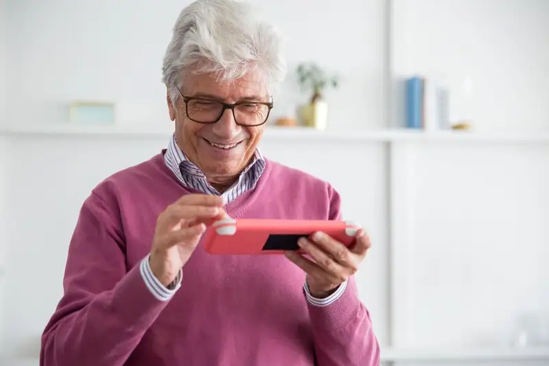 Smiling man playing a game on his smartphone – JLPUB app guide